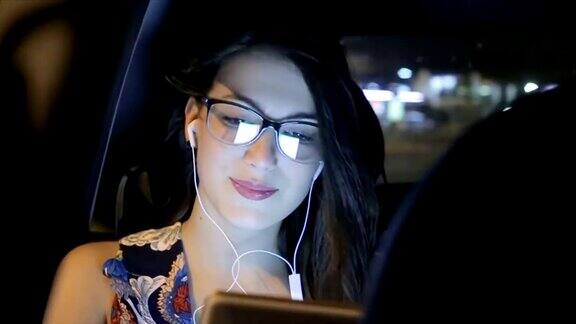 美丽的少女在车里用耳机听音乐