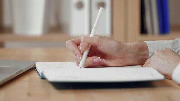 商务女性的手写就是用笔在记事本上写字用笔记本电脑