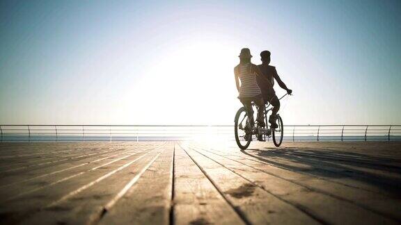 一对混血夫妇在海边的户外骑双人自行车