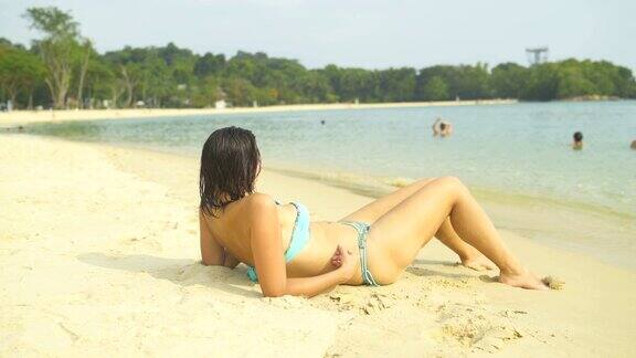 穿着泳衣的女人躺在沙滩上晒太阳