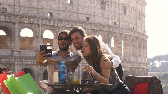 快乐的年轻夫妇游客自拍与漂亮的意大利优雅的服务员坐在酒吧餐厅在罗马斗牛场在日落开玩笑和大笑的乐趣
