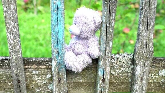孤独的玩具熊灰色毛绒儿童玩具坐在旧式的乡村围栏上