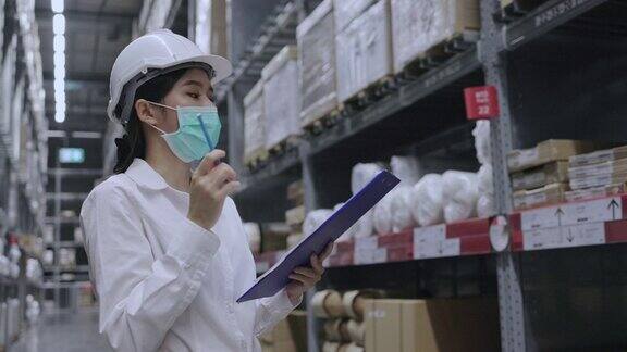 仓库工人或亚洲妇女快乐劳动佩戴医用口罩防止冠状病毒和PM2.5粉尘在运输行业工作时要戴安全帽以保护自己概念的关键员工