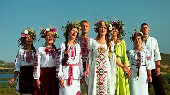一群美丽的斯拉夫男女穿着民族服装和刺绣服装在大自然中唱歌妇女头上的花圈斯拉夫民族的传统和习俗4kProRes