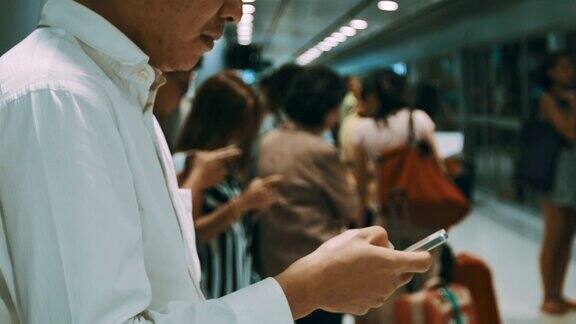 一名男子在地铁站站台上使用智能手机