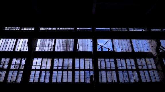 有许多窗户的老空建筑的大玻璃墙摄像机在黑暗的空间中向后移动