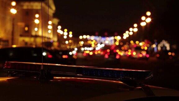 一辆交警车闪烁的灯光和夜间城市街道模糊(散焦)的背景高清视频
