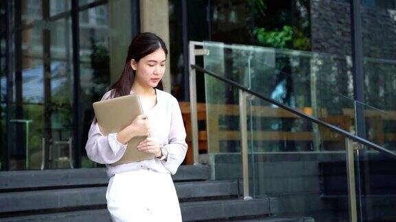 亚洲女商人在现代化的办公楼外看手表看时间赶时间开会迟到