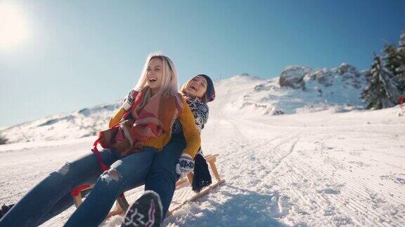 两个微笑的女朋友一起从雪山上滑下来玩得很开心