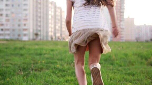夏天小女孩在城市草坪上的草地上奔跑