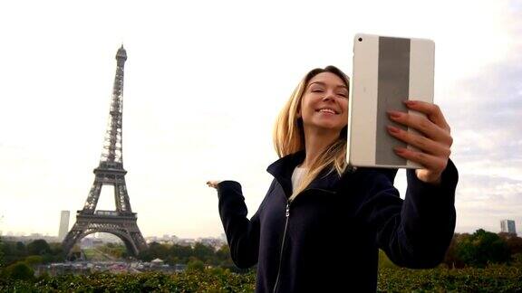 快活的女人用平板电脑以埃菲尔铁塔为背景进行视频通话