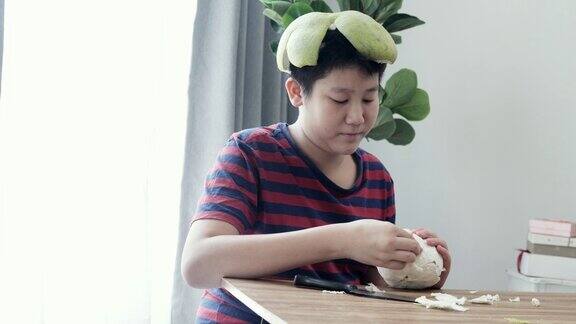 快乐的亚洲男孩坐在家里靠近窗户的地板上剥柚子生活理念