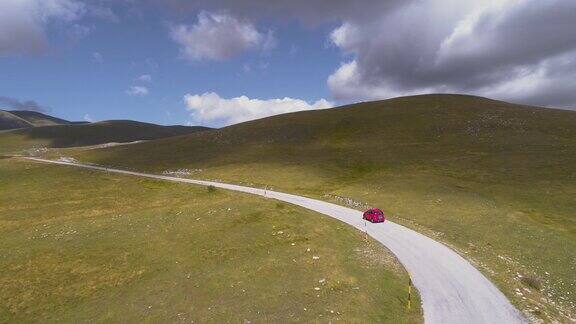航拍的红色越野车行驶在意大利蜿蜒的山路上