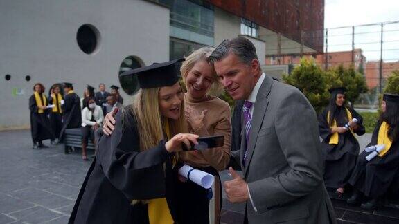 毕业典礼后美丽的女毕业生与自豪的父母自拍