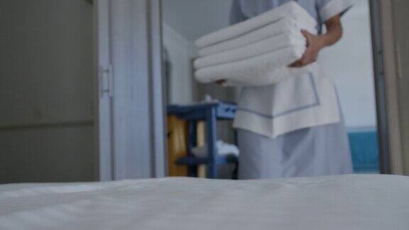 关注女清洁工为客人在床上留下干净毛巾的前景