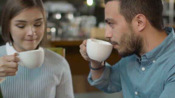 迷人的年轻男子和女子坐在舒适的咖啡店聊天