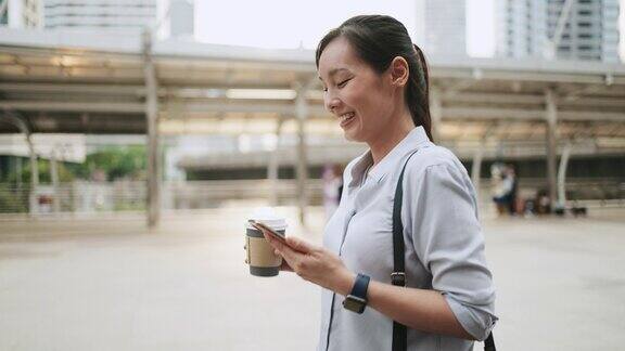 亚洲女商人在城市中行走时使用电话