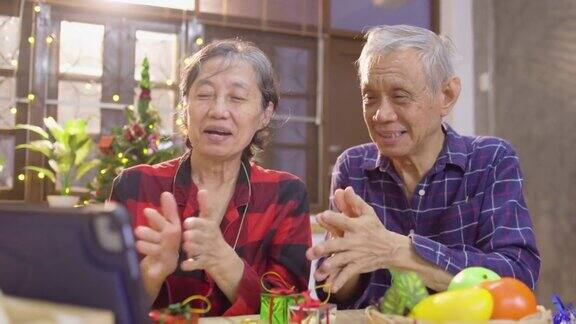 爷爷奶奶坐在客厅的公寓电话会议和笔记本电脑与孙子聊天一起庆祝传统节日在假期