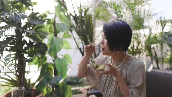 一名日本妇女午餐在户外咖啡馆吃沙拉