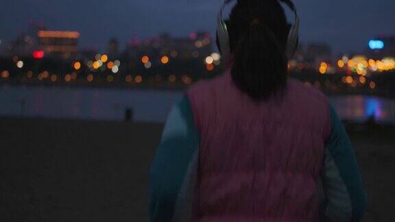 女孩戴上耳机开始在夜色中慢跑