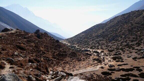 在明媚的午后阳光下徒步者和搬运工们爬上通往喜马拉雅山上珠穆朗玛峰大本营徒步旅行的路线前往尼泊尔昆布的Dinboche