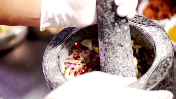 厨师用花岗岩研钵和研杵捣碎混合香料和药草原料制作泰国菜