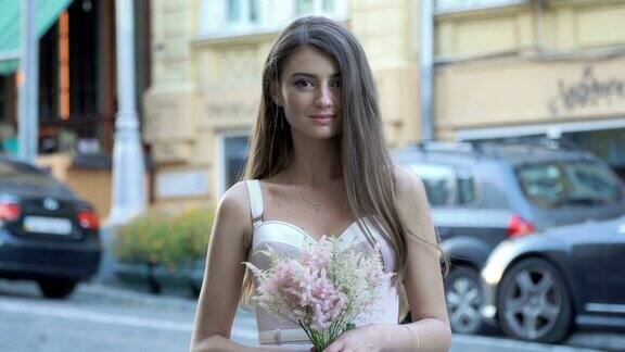 美丽的女孩带着花靠近模糊的道路