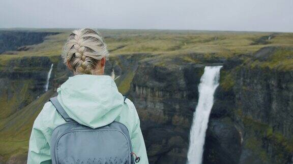 一名女子背着背包走向冰岛高地的海弗斯瀑布