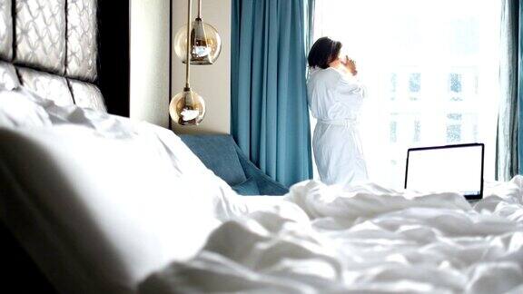 一个阳光明媚的早晨一个女人在酒店房间里喝咖啡