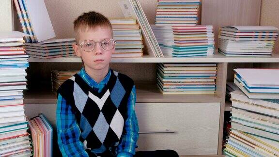 疲惫的七岁男孩戴着眼镜坐在地板上的书中