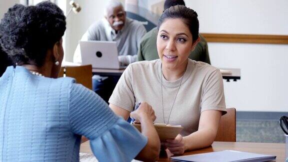 成熟的非裔美国女性银行信贷员协助女兵申请贷款