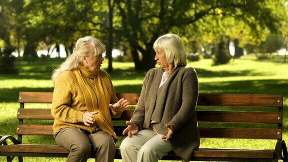 老妇人闲聊着朋友坐在公园的长椅上虚度年华