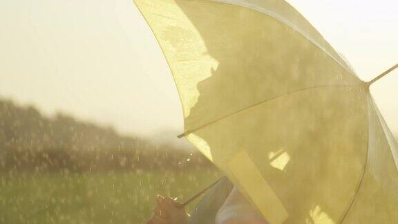 快乐的女人撑着伞旋转着用手感受着雨
