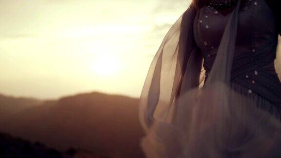 浪漫的女孩穿着长裙享受着风站在悬崖上