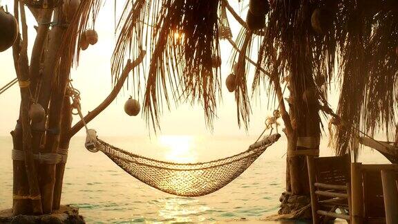 沙滩上的吊床挂在棕榈树上暑假放松