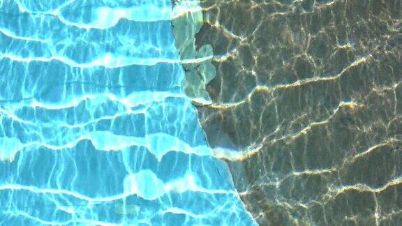 纯蓝的水在游泳池与光反射在慢动作空中镜头