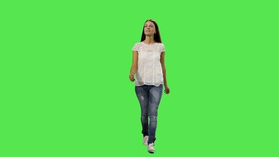 随意的年轻褐发女孩走在一个模拟绿色屏幕的背景