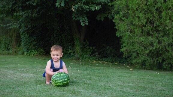 可爱的小男孩在夏天的公园草坪上玩西瓜