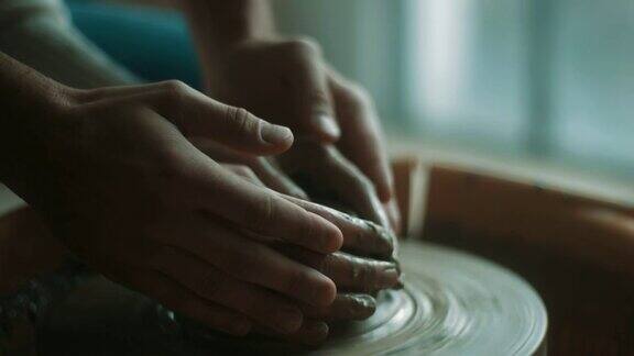 特写男人和女人的手在粘土上用陶轮