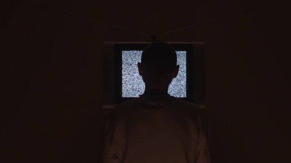 一名男子进入画面坐在电视机前电视机的静电噪声在画面的中间