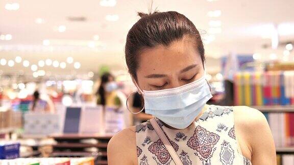年轻女子戴着防护面具和文具在超市新型冠状病毒肺炎