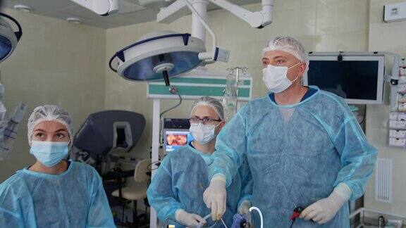 主刀外科医生在手术中使用医疗设备看着显示器显示病人的内部器官两名医生协助主刀外科医生技术在外科手术中的应用