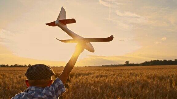 小男孩带着飞机玩具跑过麦田