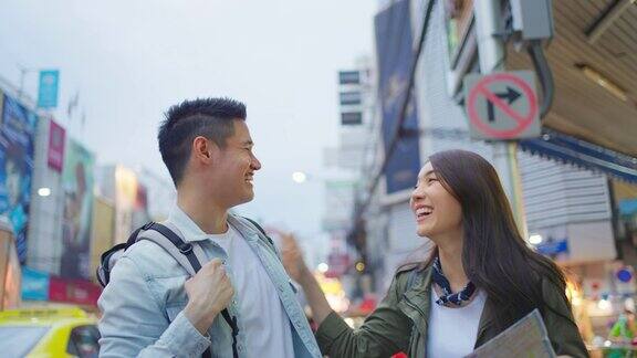 亚洲情侣在这个城市度蜜月年轻的新婚夫妇背包客们用地图找到目的地一起享受度假的时光