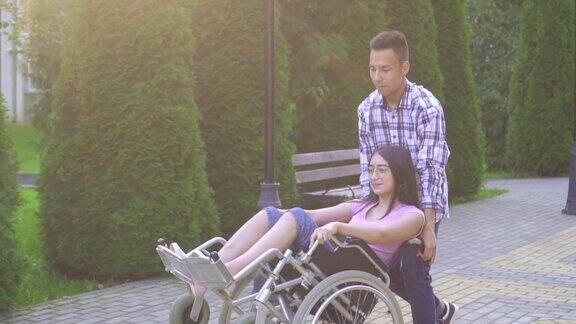 年轻积极的亚洲妇女残疾在轮椅上举起他的手她有乐趣与她的亚洲朋友在公园缓慢的mo