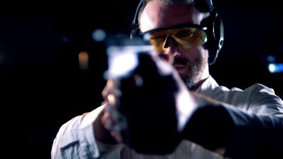 一个戴眼镜的人拿着枪在射击室特写