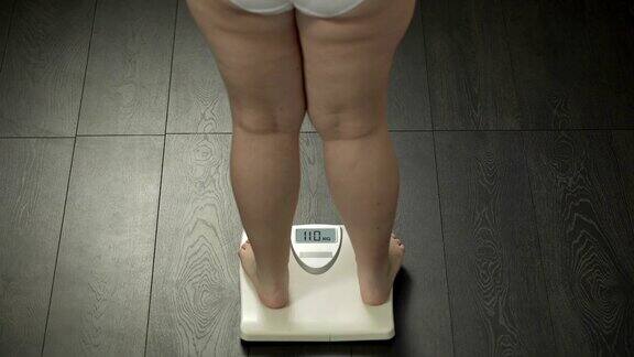 肥胖女性踩在浴室秤上检查体重脂肪后视镜