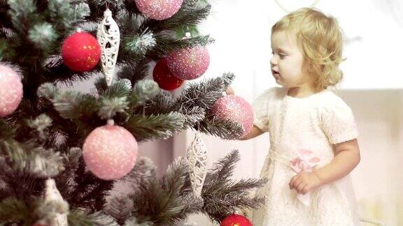 金发可爱的小女孩在玩圣诞树