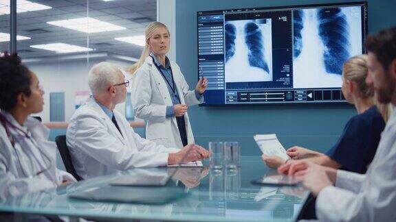 医院会议室:女医生在电视屏幕上展示病人的x光片医生小组讨论病人的治疗研究科学家谈论治疗药物医学发展