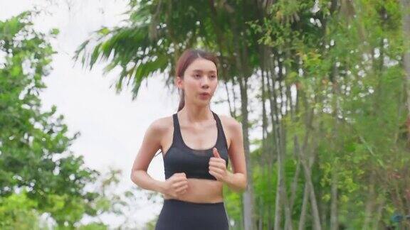 亚洲年轻美丽的运动女子在公园的街道上跑步美丽的运动员健美的女孩穿着运动服在傍晚日落的花园中进行户外慢跑健身保健